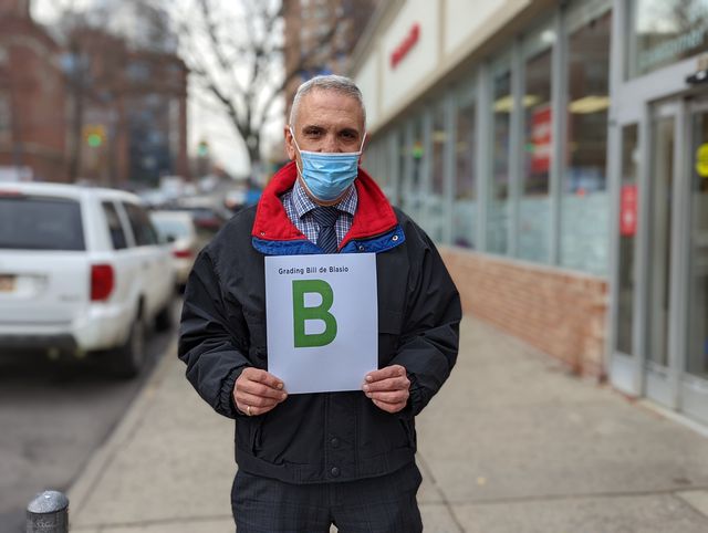 Anthony Naccari holds up a sign grading de Blasio: a "B".
